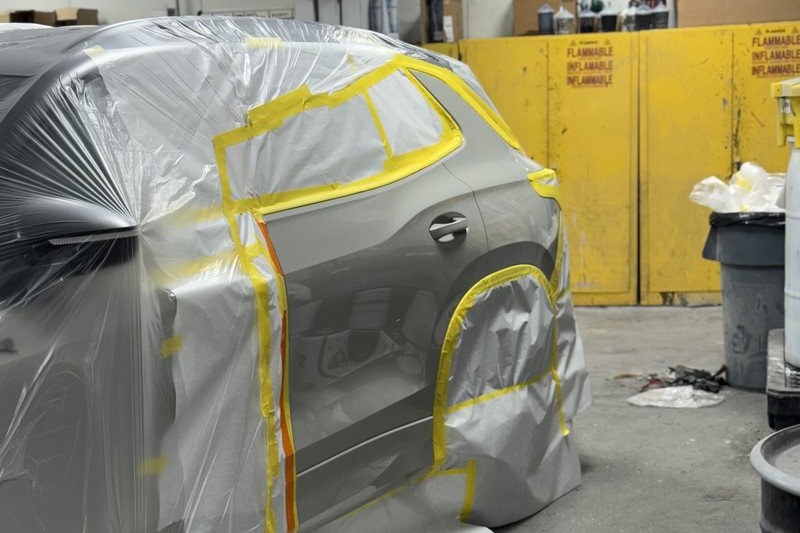 A vehicle masked and taped for refinishing in the shop